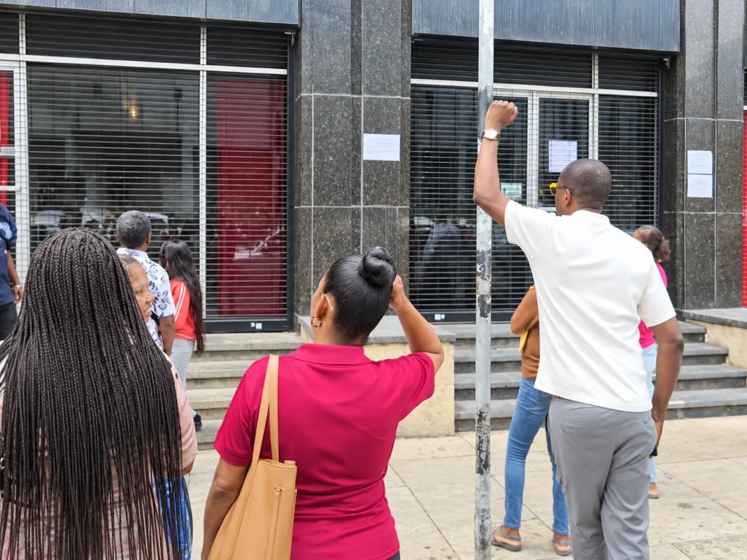 People unable to cash government cheques gather outside Treasury Building